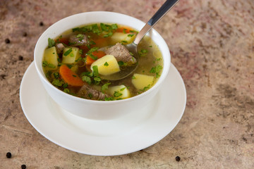Soup with meat, potatoes and carrot. Beef soup in a white bowl