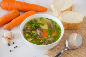 Soup with meat, potatoes and carrot. Beef soup in a white bowl