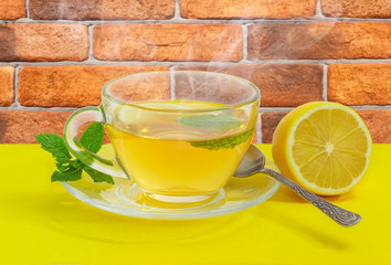 Tea with mint and lemon on a yellow surface