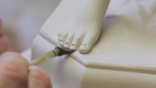 The work of the master to remove excess material on the porcelain figure.