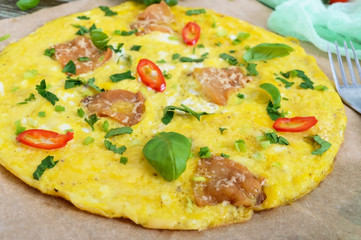 Omelette with bacon, greens and cheese on a wooden table. Breakfast. Close-up.