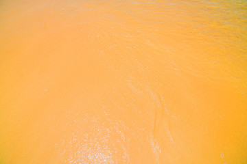 Obraz premium On the yellow sand is an ocean wave.