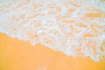 On the yellow sand is an ocean wave.