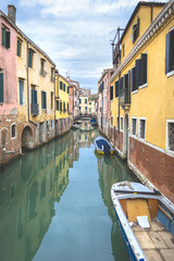 Fototapeta na wymiar Picturesque Venetian turquoise green canal boarded with colorful yellow and orange medieval building, Venice, Italy