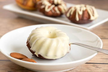 Mini bundt cake with white chocolate frosting served on white plate.