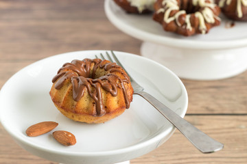 Mini bundt cake with almond, served with chocolate frosting on white plate.