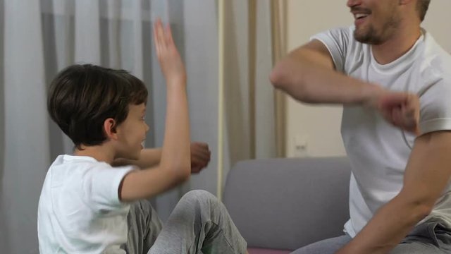 School boy making crunch exercise with father at home and giving five, sport
