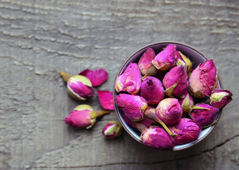 Dry rose buds flowers in a bowl on old wooden table.Healthy herbal drinks concept.Asian ingredient for aromatherapy tea.Selective focus.