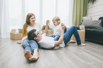 Family together happy young beautiful with a little baby moves with boxes to a new home