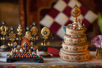The little table with the ritual mandala filled with rice and gifts and signs of happines, faces an altar in the Buddhist temple.