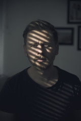 Portrait of a unhappy and depressed young man in depressive stripe environment, desaturated image
