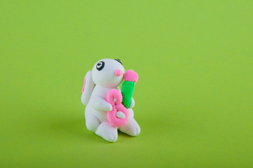 Cute small bunny made of modelling dough staying on green background