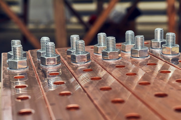 Some flat busbars with holes for fastening of electrical equipment. Metal bolts with nuts and washers are fixed in the holes. Busbars at high current and high voltage.