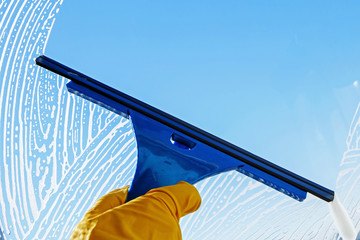Washing windows in the house. Rubber scraper in hand cleans glass from soap