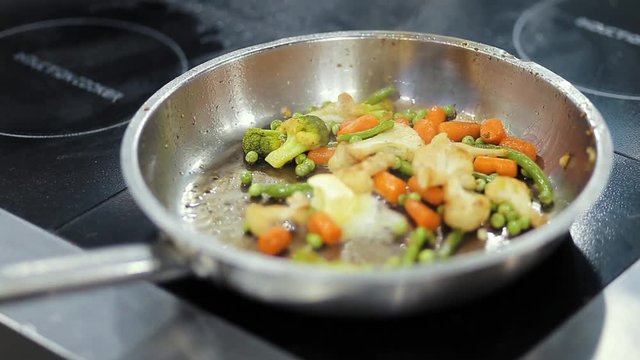 The cook bakes vegetables and frying pan