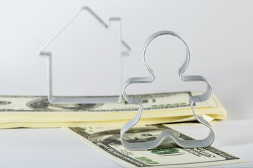 A man stands on a pack of money in front of the house