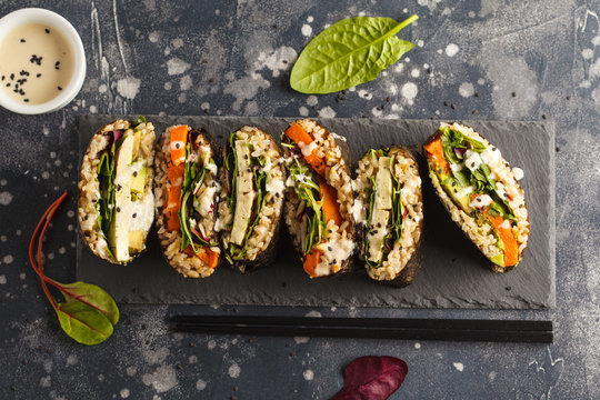 Vegan sushi sandwich onigirazu with tofu and vegetables. Colorful japan sandwich onigirazu with tofu, sweet potato, avocado and tahini. Trend vegan food concept. Top view, copy space.