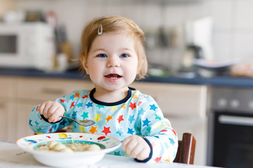 Adorable baby girl eating from spoon vegetable noodle soup. food, child, feeding and people concept