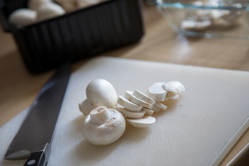 Weiße Champignons werden in Küche mit Messer in Scheiben geschnitten