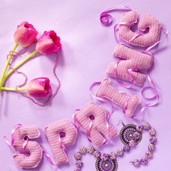 tulip floweres and spring word from knitted letters on pink paper