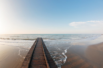 Obraz premium Wooden pier. Beach of Lido di Jesolo at adriatic Sea in a beautiful summer day Italy. near Venice. dense sea breeze at dawn