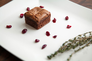  Chocolate dessert with berries and herbs, decorated on a white plate.