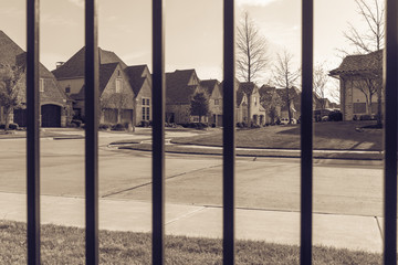 View of nice, comfortable neighborhood thru fence. Nicely trimmed and manicured garden in front of street of homes in suburbs of Irving, Texas, USA. Security and protection concept. Vintage tone