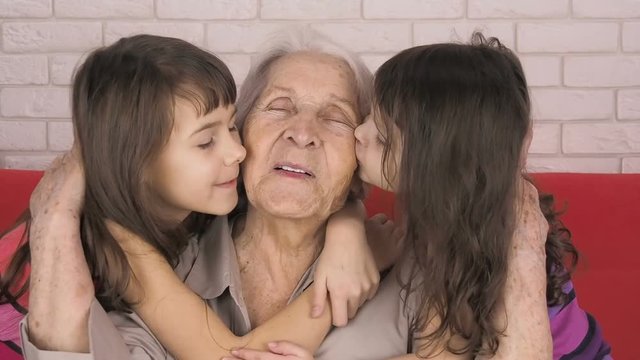 Grandmother with granddaughters. Children kiss grandmother.