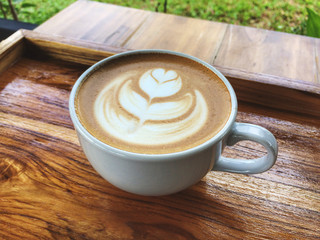 Latte coffee art on the wooden tray and table with garden view, Full fill energy cup. Fresh and relaxing.