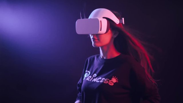 Girl in white virtual reality glasses, running, neon colored lighting.
