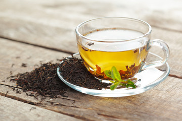 cup of black tea with mint leaves on a wooden table