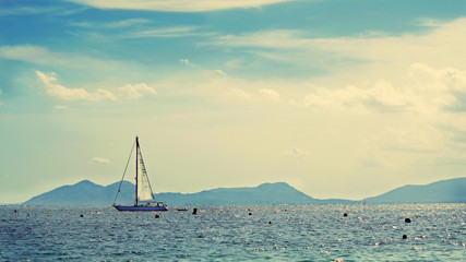 Fototapeta premium White sailboat n the distance. The coast of Mediterranean sea, Mallorca, Spain.