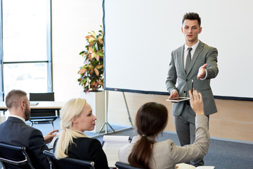 Portrait of handsome successful businessman answering questions from audience during training...