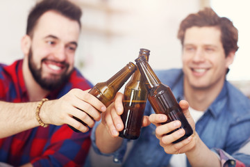 Happy male friends cheering and watching sports on tv