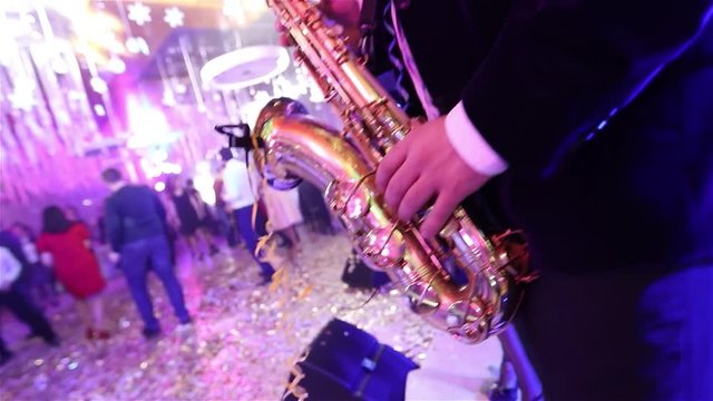 Male saxophonist with a musical band playing on stage in a restaurant, a saxophonist playing, shallow depth of field