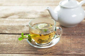 cup of black tea with mint leaves on a wooden table