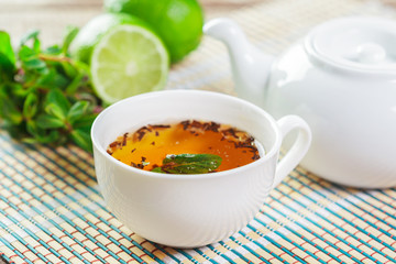 cup of black tea with mint leaves on a wooden table
