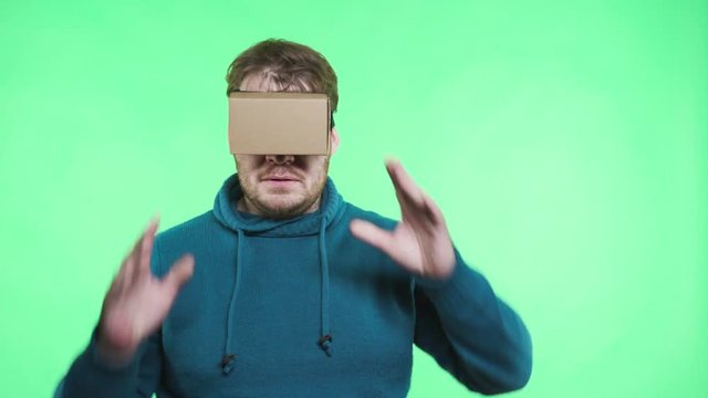 One adult guy shocked look in spectacles in chromakey greenbox isolated close up. Gamer male person playing, move watch something in emulator glasses. Advertising concept enjoyment life style