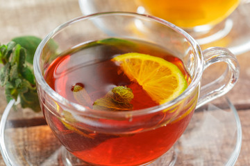 cup of black tea with mint leaves on a wooden table