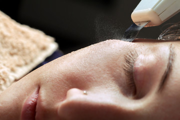 Woman face skin scrubber treatment with ultrasonic spatula