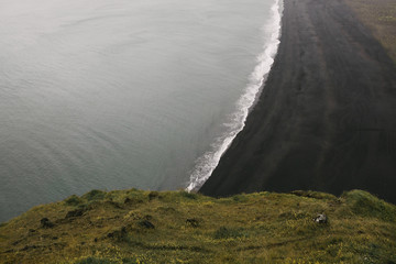 beautiful view at wavy ocean and black sand at icelandic shore, vik dyrholaey, reynisfjara beach, iceland