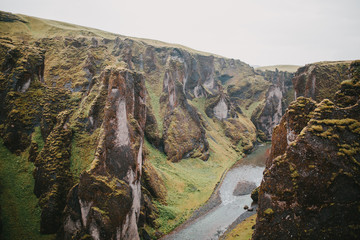 Fototapeta na wymiar majestic rocky mountains with green vegetation and small river in fjadrargljufur, iceland