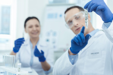 Have a look. Professional man working in a lab while holding a test tube