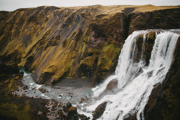 Fototapeta na wymiar scenic icelandic landscape with majestic Fagrifoss waterfall and rocks with green vegetation