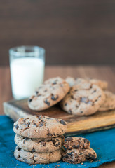double chocolate chip cookies gestapelt auf blauem tuch und dunklem untergrund vor dunklem hintergrund mit einem glas milch