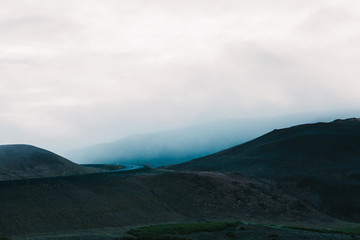 majestic icelandic landscape with hills and asphalt road at cloudy day