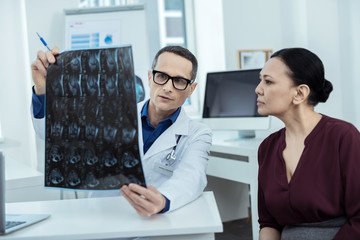 Important occupation. Professional doctor holding a mri scan while talking with his patient