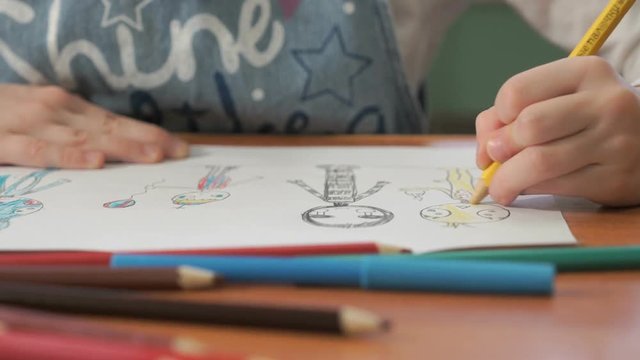 Close-up of unknown child draws the pictures using color pencils in the album in the kindergarten