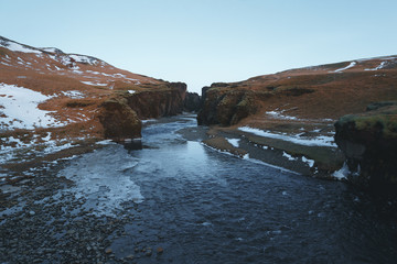 beautiful landscape with cold river, rocks and snow, fjadrargljufur, iceland