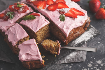 Yogurt pound cake for breakfast with pink glaze and fresh strawberries. Dark background, summer berry dessert, copy space.